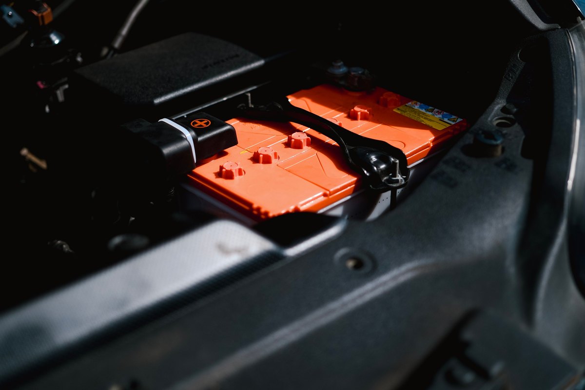 A twelve-volt battery clamped in place in an engine bay